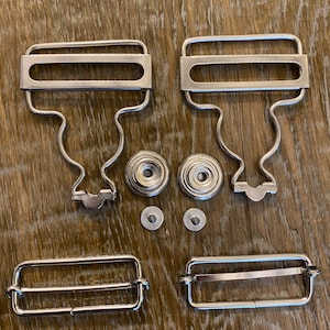 Puede incluir: Un juego de cierres de metal plateado para sujetar correas o cinturones. El juego incluye dos pares de cierres, dos pares de tachuelas y dos pares de anillos.