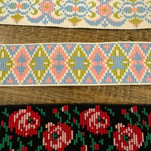 May include: Three different types of trim with geometric and floral patterns. The top trim is white with blue, pink, and green geometric shapes. The middle trim is white with blue, pink, and green diamond shapes. The bottom trim is black with red and green floral shapes.