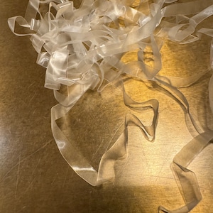 May include: A pile of clear elastic bands on a gold surface.
