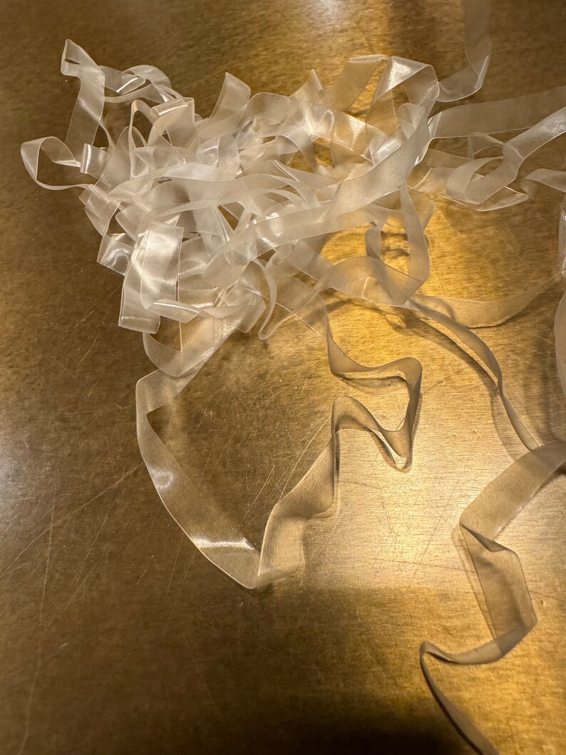 May include: A pile of clear elastic bands on a gold surface.