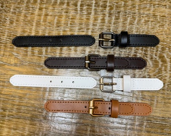May include: Four leather straps with metal buckles. The straps are brown, black, white, and tan. The buckles are gold.