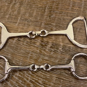 Può includere: Due morsi per cavalli in argento, uno con un anello a D e uno con un anello rotondo. Entrambi i morsi hanno una boccaglio articolato.