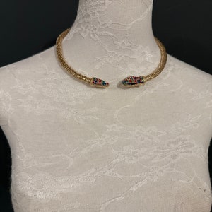 May include: A gold snake-shaped choker necklace with colourful rhinestones on the snake's head.