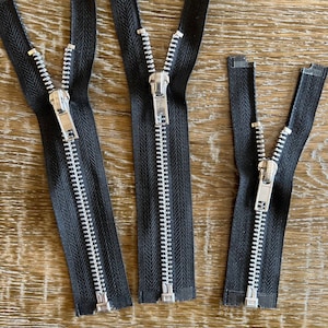 May include: Three black zipper closures with silver teeth. The zippers are different lengths.