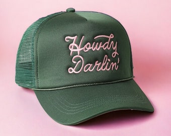 Puede incluir: Una gorra de camionero verde con un diseño bordado en rosa que dice "Howdy Darlin'"