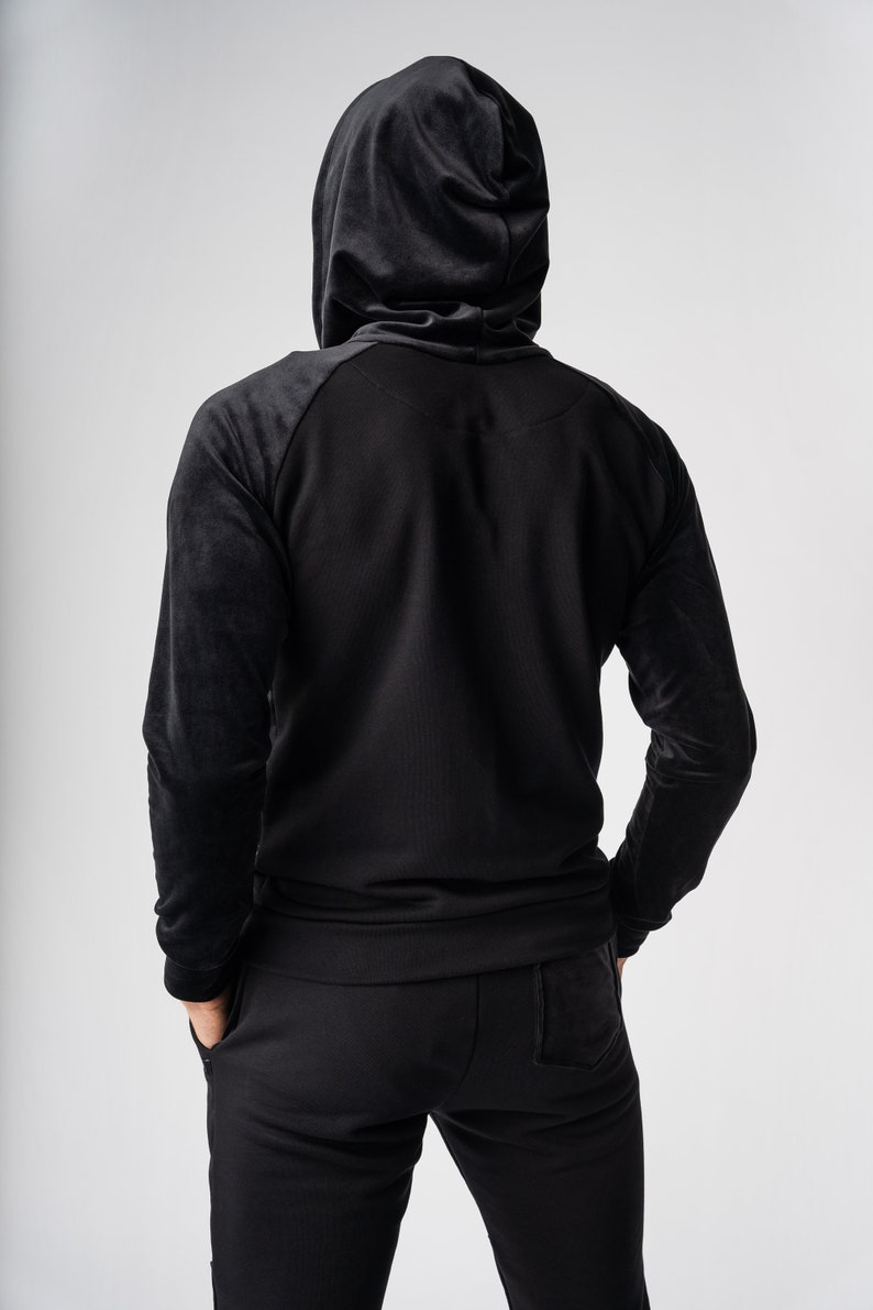 May include: A black hooded sweatshirt with a zipper closure and a matching pair of black sweatpants.