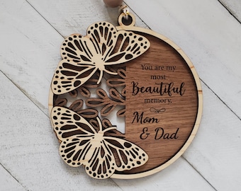 May include: A wooden ornament with two cutout butterflies and the text "You are my most beautiful memory. Mom & Dad"