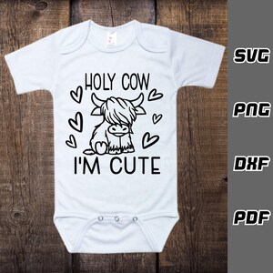 May include: White baby onesie with black text that reads "HOLY COW I'M CUTE". A black and white cartoon Highland cow with hearts around it is featured on the onesie.