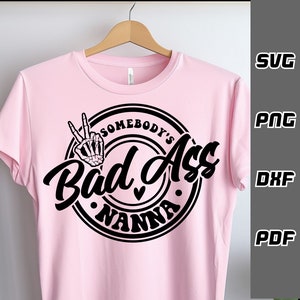 May include: Pink t-shirt with a black circle design that says "Somebody's Bad Ass Nanna" with a skeleton hand making a peace sign.