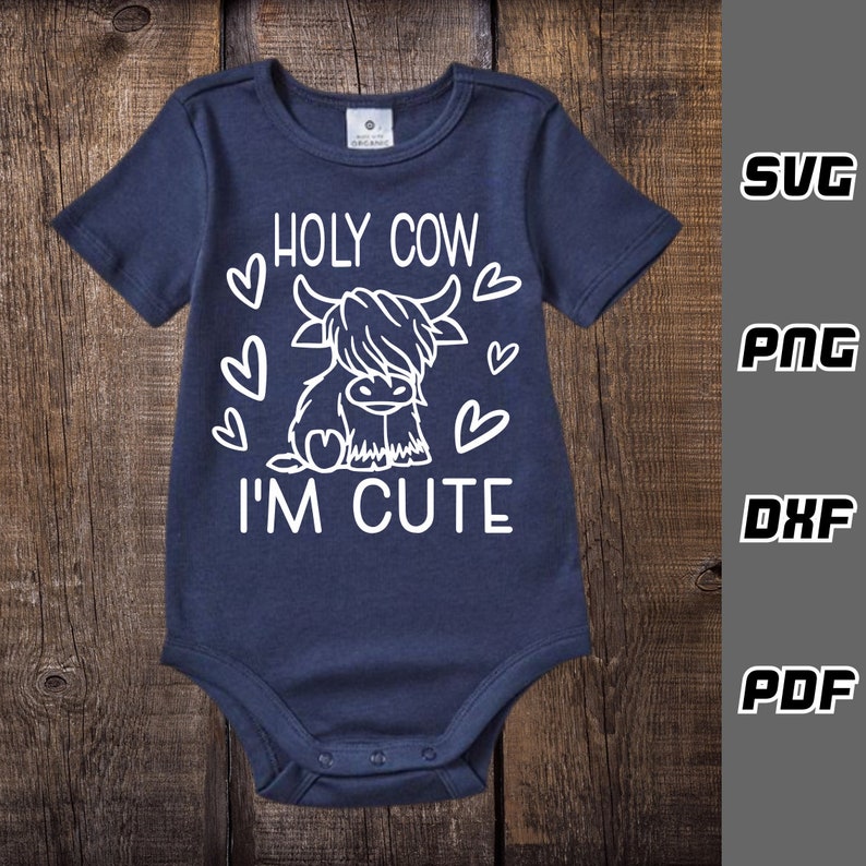 May include: A navy blue baby onesie with a white graphic of a Highland cow with the text "HOLY COW I'M CUTE" and hearts around the cow.