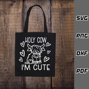 May include: Black tote bag with a white design of a Highland cow with the text "HOLY COW I'M CUTE" and hearts around the cow.