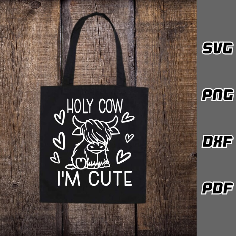 May include: Black tote bag with a white design of a Highland cow with the text "HOLY COW I'M CUTE" and hearts around the cow.