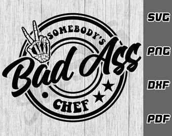 May include: Black and white graphic design of a skull hand giving a peace sign with the text "Somebody's Bad Ass Chef" in a circle.