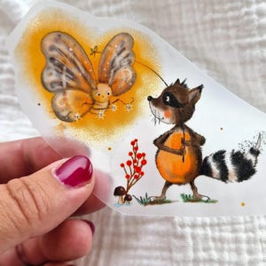 May include: A raccoon with a black mask and a striped tail looks up at a yellow butterfly with brown wings. The butterfly is surrounded by a yellow glow. The raccoon is holding a small orange object in its paws. There are red berries and mushrooms in the background.