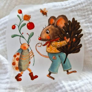 May include: A whimsical illustration of a mouse carrying a brown pine branch, a ladybug with orange spots, and a small red berry plant. The mouse is wearing blue pants and a yellow sweater with white flowers.