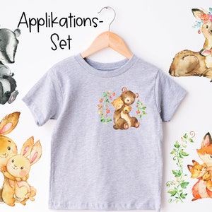 Könnte beinhalten: Ein Set mit fünf Bügelbildern mit Aquarell-Illustrationen von Tieren mit ihren Babys. Die Tiere sind ein Dachs, ein Bär, ein Reh, ein Kaninchen und ein Fuchs. Die Transfers sind perfekt, um Kleidung, Taschen oder anderen Stoffartikeln einen Hauch von Verspieltheit zu verleihen.