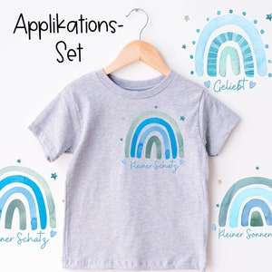 Puede incluir: Un conjunto de tres parches para planchar que presentan arcoíris de acuarela con estrellas y texto en alemán. Los parches dicen "Kleiner Schatz" y "Kleiner Sonnenschein".