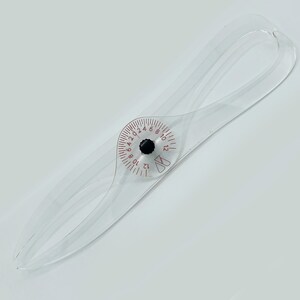 May include: A clear plastic tool with a circular gauge marked with numbers from 1 to 24. The gauge has a black pointer and is used to measure the circumference of an object.