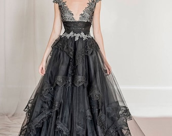 Könnte beinhalten: Ein schwarzes Tüllkleid mit einem Spitzenoberteil und einem mehrlagigen Rock. Das Kleid hat einen herzförmigen Ausschnitt und kurze Ärmel. Das Spitzenoberteil ist mit silbernen Pailletten verziert.