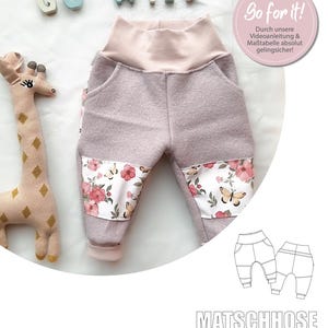 May include: A pair of purple sweatpants with a floral print on the bottom. The sweatpants have a pink waistband and are designed for children. The text "Go for it!" is visible in the image. The text "Durch unsere Videoanleitung & Maßtabelle absolut gelingsicher!" is also visible in the image. The text "MATSCHHOSE LEONA" is visible at the bottom of the image.
