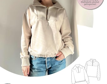 May include: A beige, long-sleeved, cropped sweatshirt with a zipper and a high collar. The sweatshirt has a pattern of small squares on the sleeves. The text "Go for it!" is written in a pink circle. The text "Durch unsere Videoanleitung & Maßtabelle absolut gelingsicher!" is written below the circle. The text "COZY TROYER" is written in black at the bottom of the image.