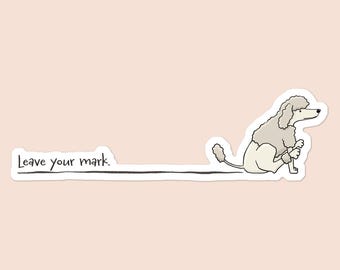 May include: A sticker featuring a cartoon poodle sitting and holding a pencil, with a black line extending from the pencil. The text "Leave your mark" is written in black. The background is a light pink color.