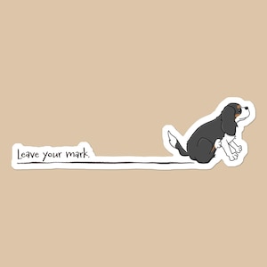 May include: A sticker featuring a cartoon dog in black, white, and tan, sitting and leaving a trail. The text "Leave your mark" is above the trail. The background is a solid tan color.