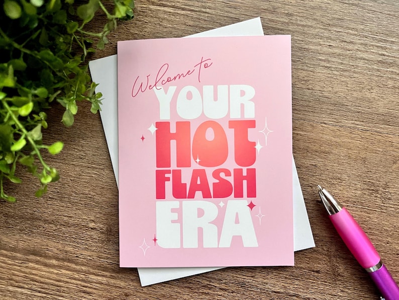 May include: A pink card with white text that reads "Welcome to your hot flash era". The text is in a bold, playful font. There are small white stars scattered around the text.