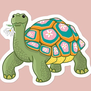 May include: A green turtle with a colorful shell decorated with pink and white flowers. The turtle is walking and holding a white flower in its mouth.