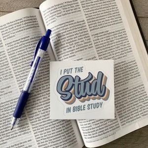 May include: A sticker with a blue, white, and orange design that says "I Put the Stud in Bible Study".
