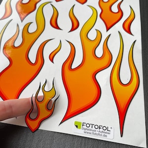 Könnte beinhalten: Eine Bogen mit orangefarbenen und gelben Flammenaufklebern mit dem Text "FOTOFOL Digitaldruck - Aufkleber www.fotofol.de" in der rechten unteren Ecke.