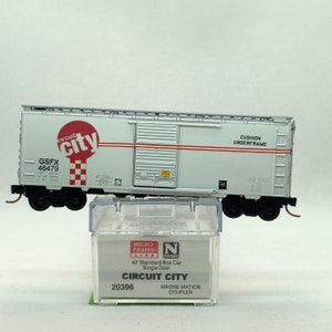 May include: A white model train boxcar with red stripes and the words "Circuit City" and "GSFX 46479" printed on the side. The boxcar is on a clear plastic base and has a black and white checkered pattern on the side. The boxcar is labeled "40' Standard Box Car Single Door" and "Circuit City" with the model number "20396".