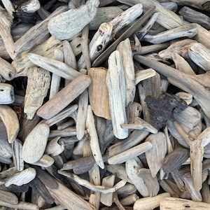 May include: A collection of weathered driftwood pieces in various shapes and sizes. The wood tones range from light gray to dark brown, with some pieces showing natural textures and knots. Ideal for crafting or home decor.