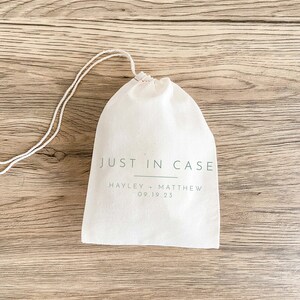 May include: A white cotton drawstring bag with the text "JUST IN CASE" and "HAYLEY + MATTHEW 09.19.23" printed in green.