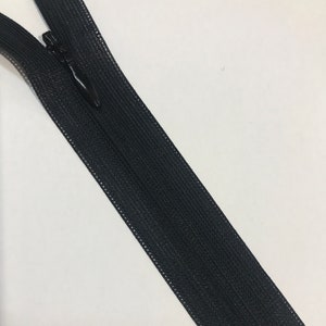 May include: Black zipper tape with a black zipper pull. The zipper tape is made of a woven fabric.