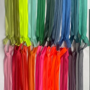 May include: A collection of colourful zipper tapes in various shades of green, blue, red, orange, and pink. The zipper tapes are arranged in rows and are ready to be used for sewing projects.