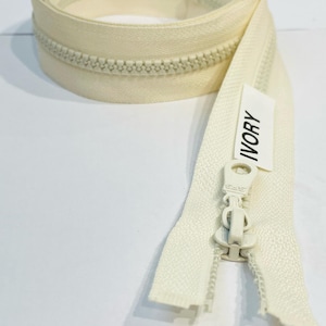 May include: A white zipper with a plastic slider and a label that says "IVORY".