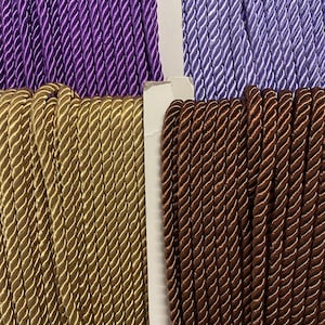 May include: Four spools of twisted cord in purple, light blue, gold, and brown.