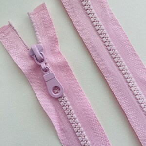 May include: Two pink zipper tapes with a plastic zipper pull. The zipper pull is light purple.