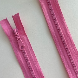 May include: Two pink zipper closures with a plastic slider and a metal pull tab. The zipper teeth are visible and the zipper tape is smooth.
