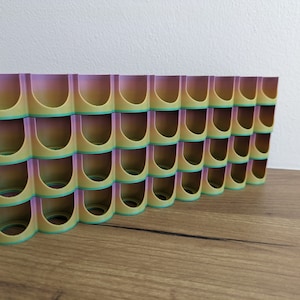 May include: A 3D printed organiser with multiple compartments, featuring a gradient colour scheme of purple, yellow and green.