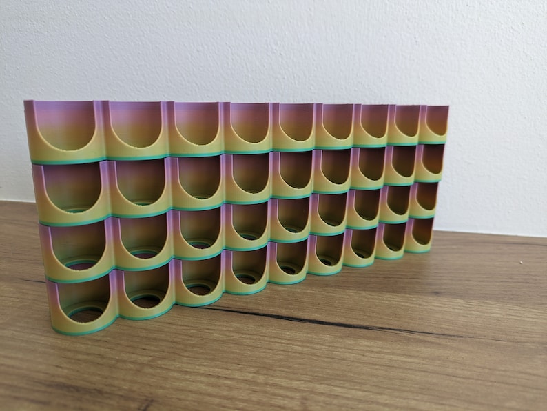 May include: A 3D printed organiser with multiple compartments, featuring a gradient colour scheme of purple, yellow and green.