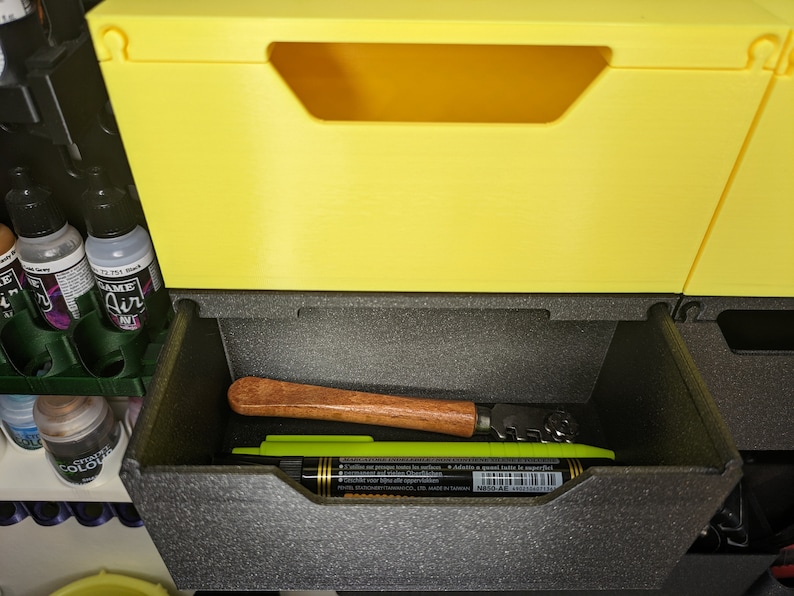 May include: A yellow plastic storage bin with a black foam insert. The insert has a wooden tool and a green marker inside.