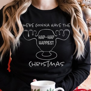 May include: A black long-sleeved shirt with a white graphic of a moose head and the text "We're gonna have the hap-hap happiest Christmas".
