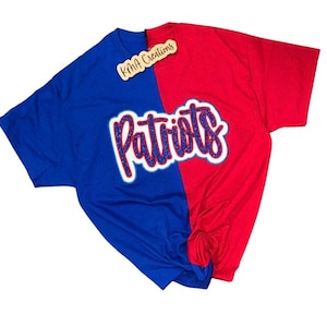 May include: A two-toned t-shirt, split vertically into blue and red sections. The word "Patriots" is prominently displayed in a glittery, white-outlined font across the shirt's center. A small tag with the text "KMA Creations" is attached.