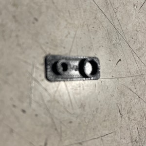 May include: A black plastic rectangular piece with two round holes.