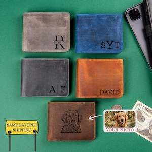 May include: Five leather wallets in various colors: gray, blue, black, and brown. Each wallet is personalized with initials, names, or a dog portrait. The wallets are displayed with a phone, money, and a small photo.