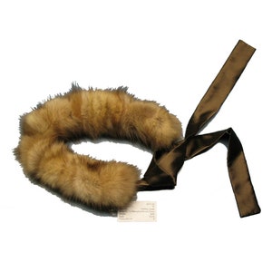 Puede incluir: Un collar de piel marrón con un lazo de cinta de satén marrón.