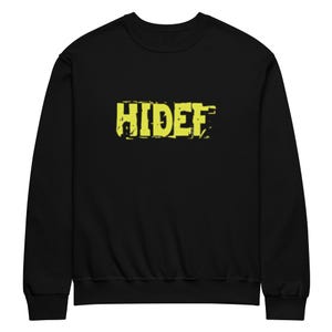 Può includere: Felpa nera con la scritta "HiDef" in giallo, con un carattere invecchiato sul petto. La felpa ha un girocollo e maniche lunghe. Il tessuto sembra morbido.