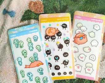 May include: Three rectangular sticker sheets featuring Ghibli characters. The left sheet shows green Kodama figures and a pink creature. The center sheet displays black Soot Sprites and colorful stars. The right sheet features white Warawara figures.
